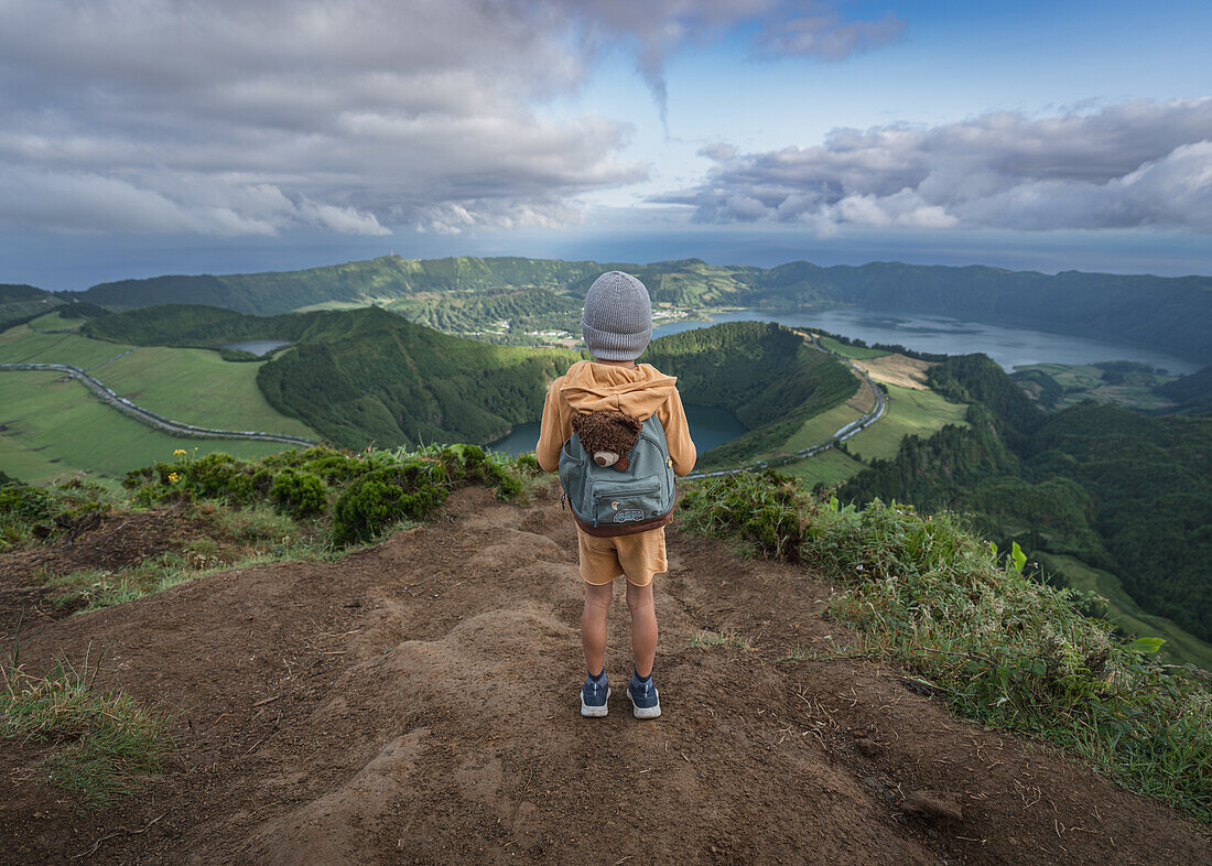  Little boy with his teddy bear at the Miradouro da Boca do Inferno viewpoint overlooking the volcanic lakes in Sete Cidades on the island of Sao Miguel, Azores. 