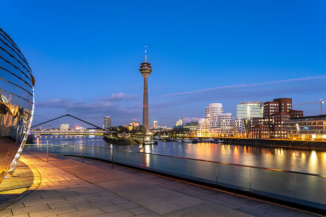  View from the terrace of the Hyatt Hotel to the Gehry buildings - Neuer Zollhof at the Media Harbor and the Rhine Tower in Düsseldorf at dusk, North Rhine-Westphalia, Germany  