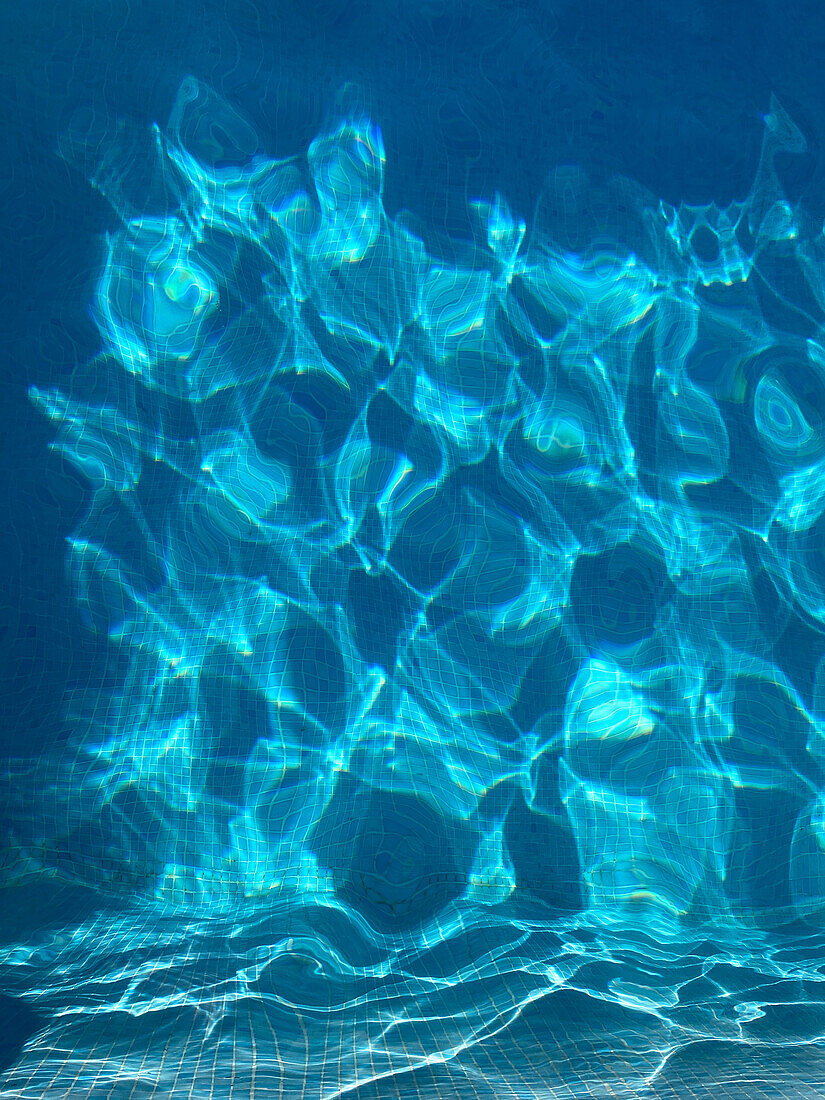 Lichtreflexionen unter Wasser bei Sonnenschein in einem Swimming Pool im Sommer