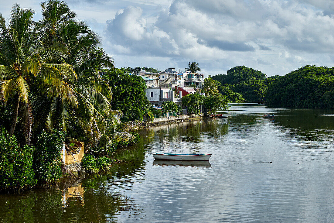Boot und Palmen, Häuser an einem Ufer von einem Fluss, Mauritius, Afrika
