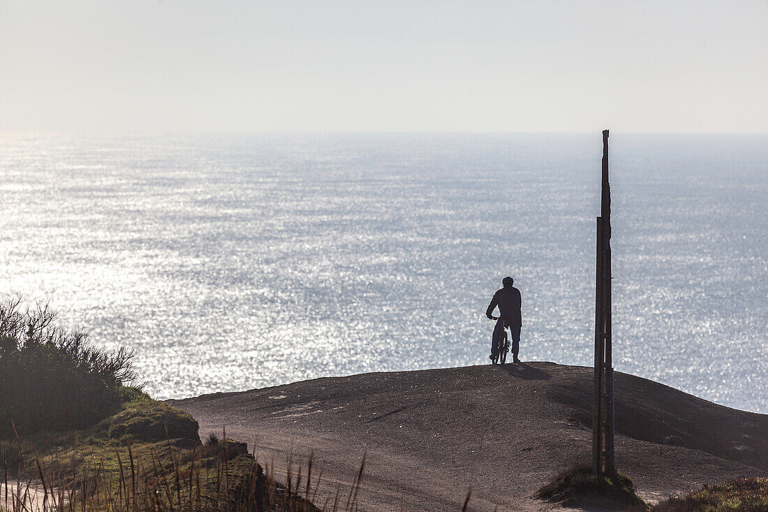 Mann mit Fahrrad vor dem glitzernden Meer, Atlantikküste, West-Frankreich, Frankreich