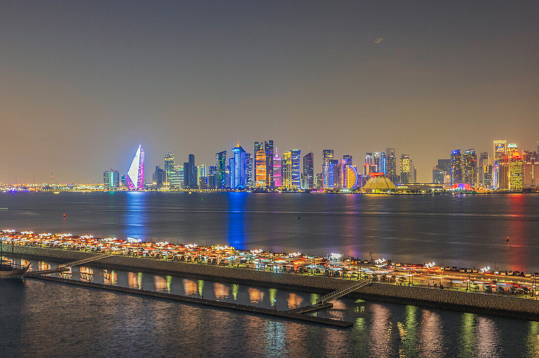 Blick auf die bunt beleuchtete Skyline am Pier des alten Dhau Hafens bei Nacht, Hauptstadt Doha, Emirat Katar, Persischer Golf