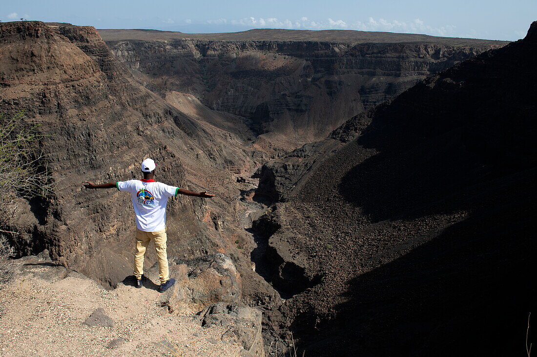 Einheimischer Mann breitet die Arme aus und blickt auf den Belvedere Sul Canyon, in der Nähe von Arta, Dschibuti, Naher Osten