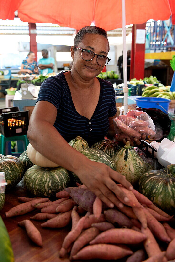 Einheimische Frau verkauft Yamswurzeln auf dem Victoria-Markt, Victoria, Insel Mahé, Seychellen, Indischer Ozean