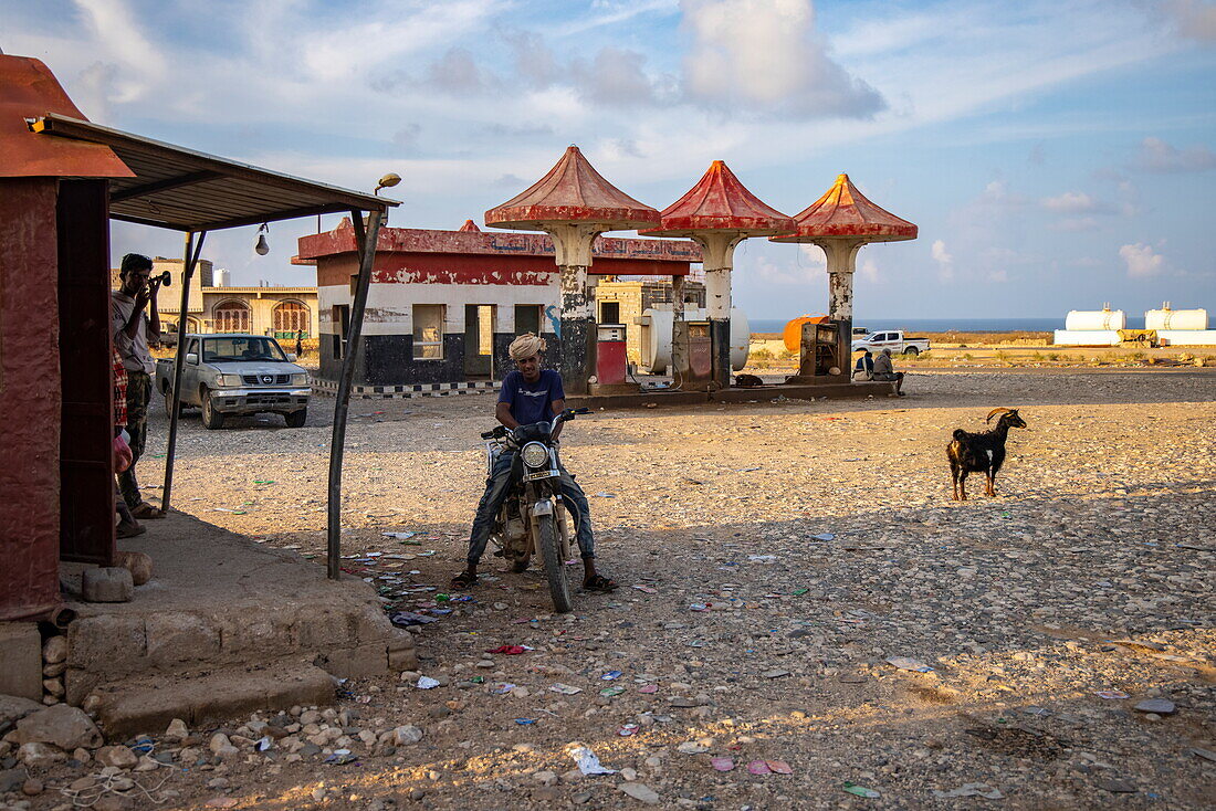  Man on motorcycle and goat at gas station, Socotra Island, Yemen, Middle East 