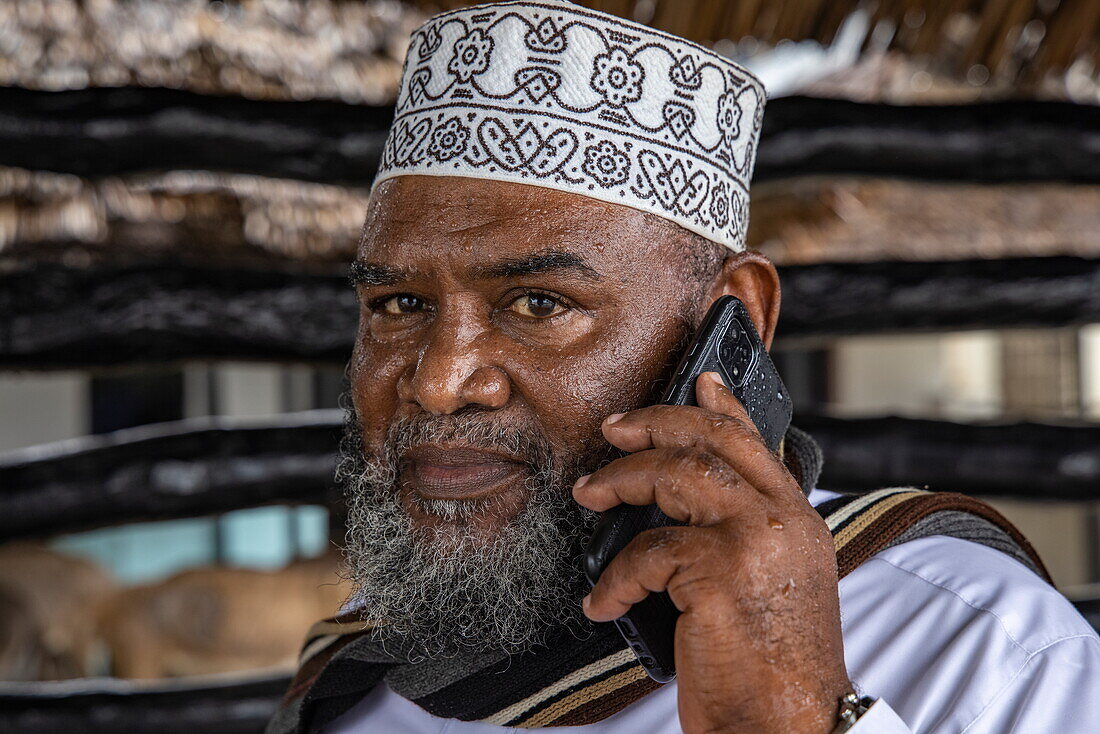 Mann mit muslimischem Taqiyah-Hut und Mobiltelefon in der Hand, Lamu, Insel Lamu, Kenia, Afrika