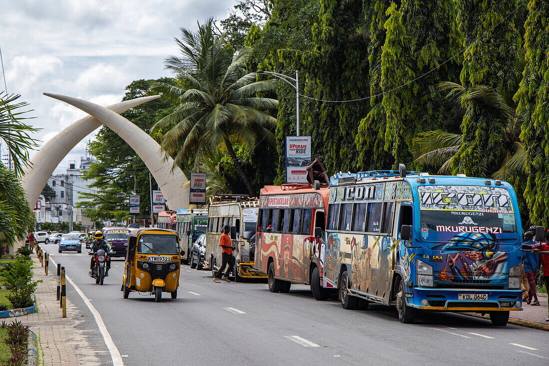 Bunte Busse und Tuk-Tuk, vor dem Stoßzähne-Denkmal auf der Moi Avenue, Mombasa, Kenia, Afrika