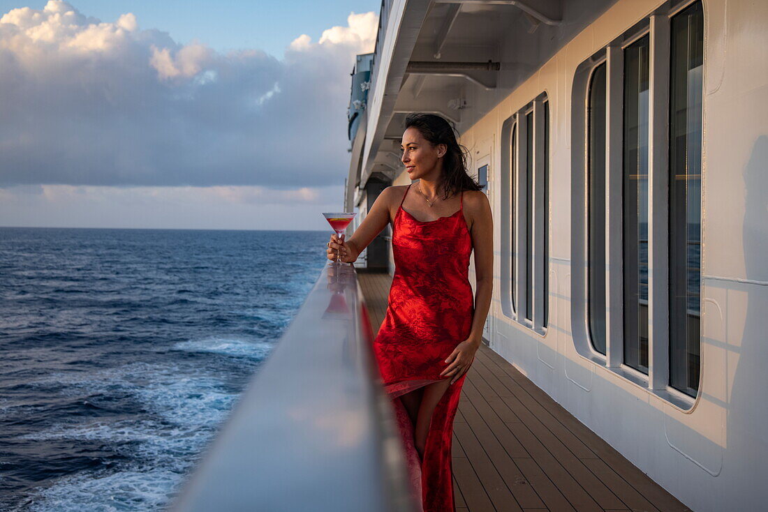  Woman with cocktail glass on the railing of the expedition cruise ship SH Diana (Swan Hellenic), at sea, near the Seychelles, Indian Ocean 