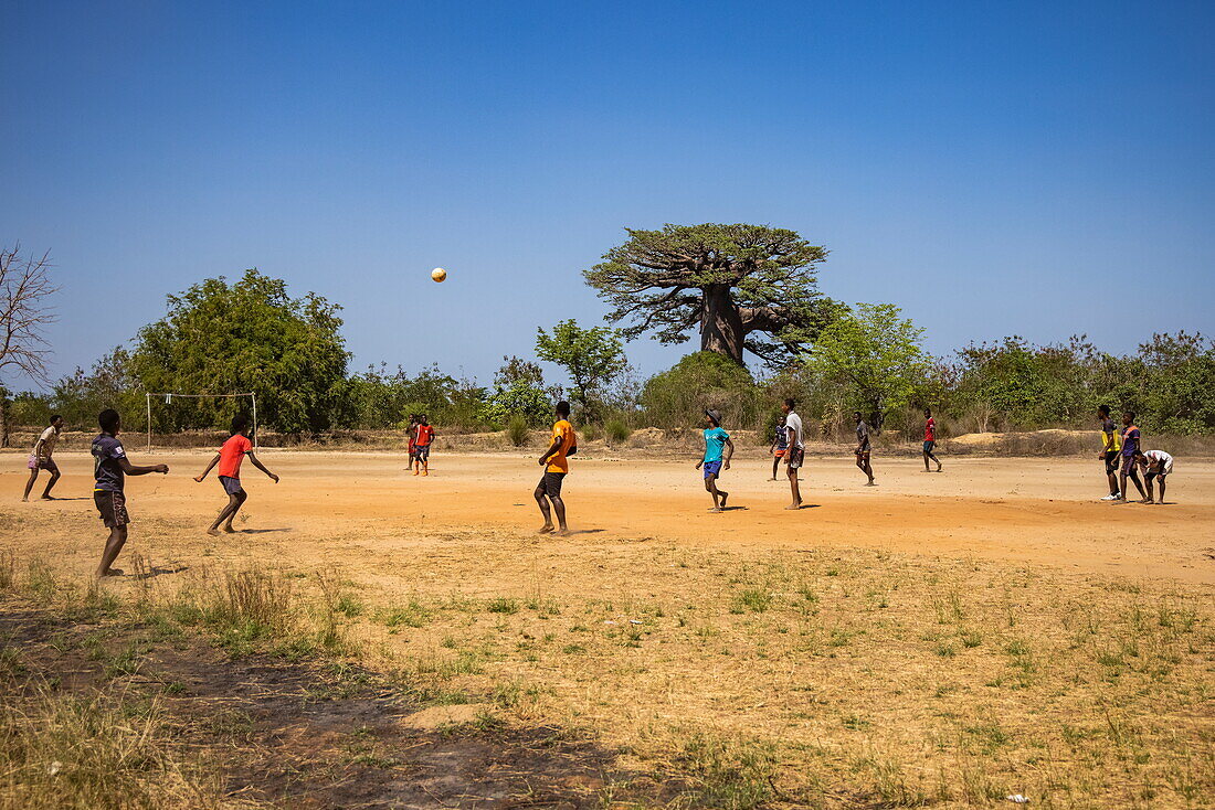 Einheimmische Jungen spielen Fußball auf einem unbefestigten Feld in der Nähe von Morondava, Menabe, Madagaskar, Indischer Ozean