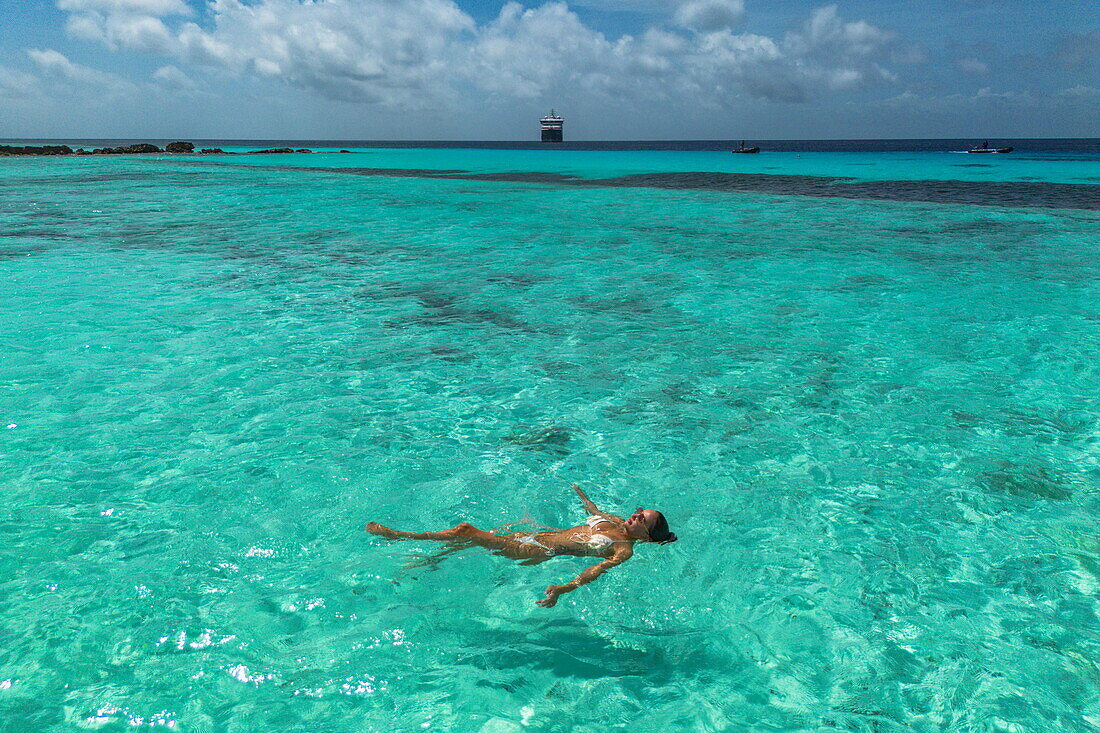  Aerial view of a woman swimming in shallow water with the expedition cruise ship SH Diana (Swan Hellenic) in the distance, Assumption Island, Outer Islands, Seychelles, Indian Ocean 