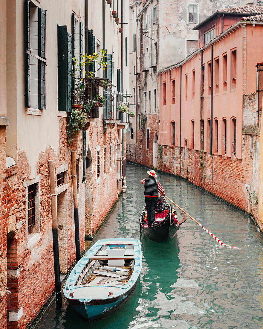 A gondolier navigates the quieter canals of Venice in Italy.