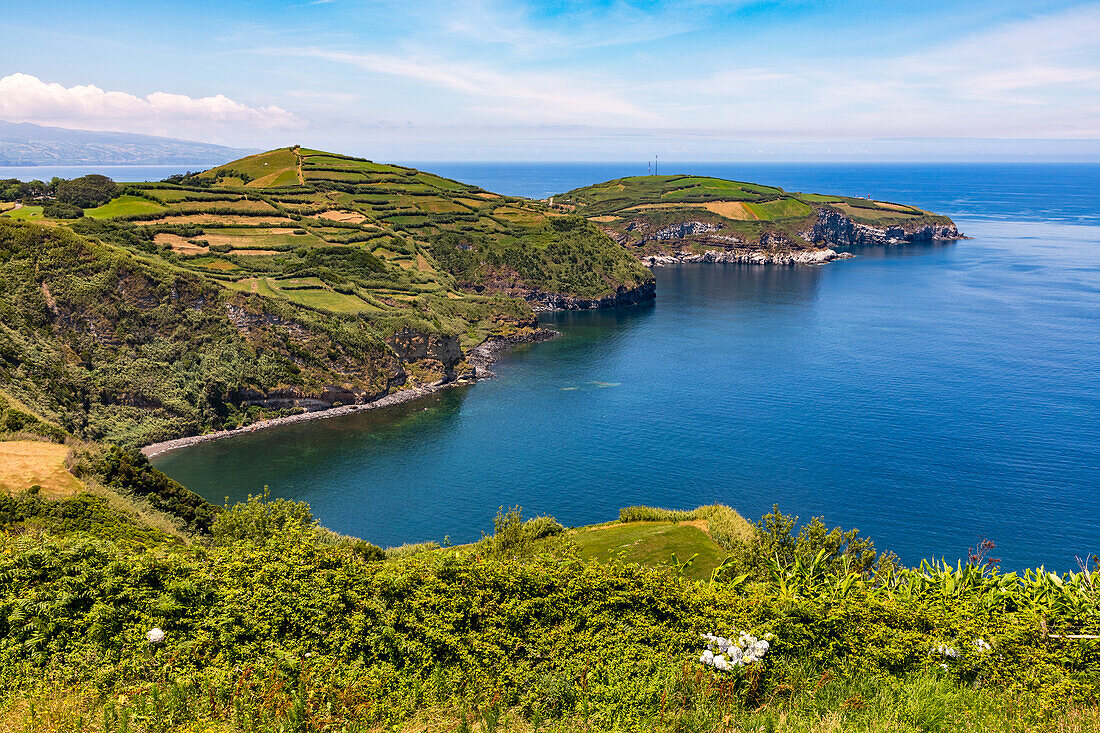  Lava rocks and agricultural fields stretch far out into the azure sea on a peninsula to the east of the Portuguese island of Flores, Azores, Portugal. 