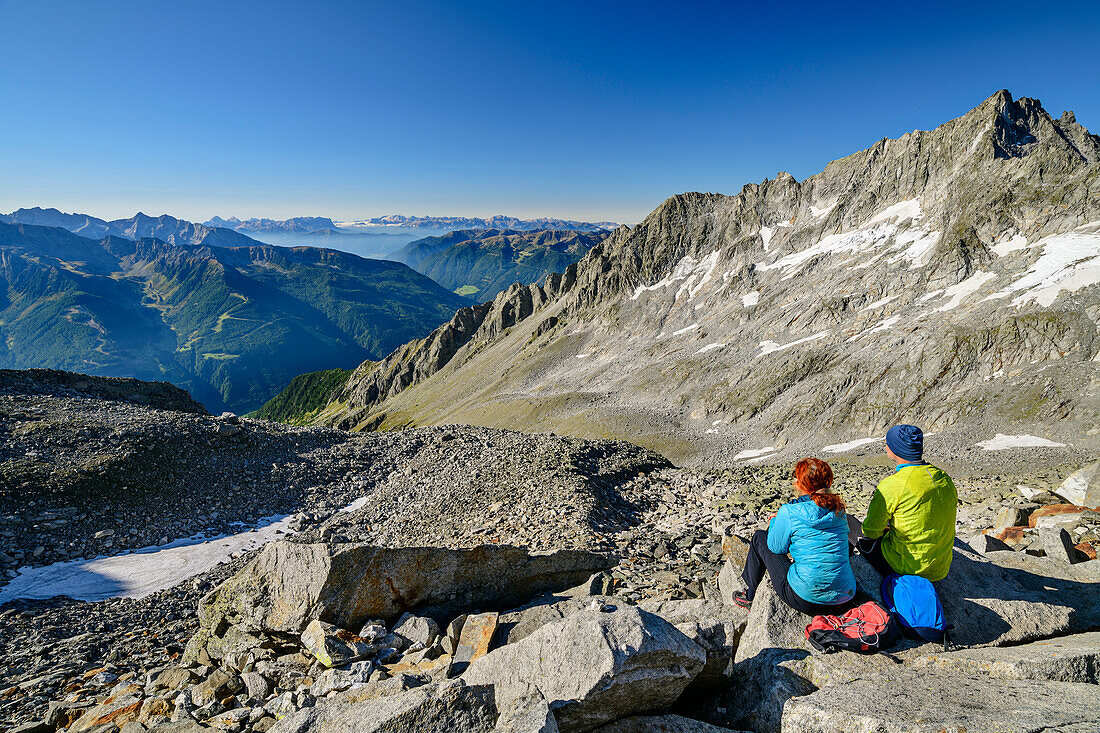 Mann und Frau beim Wandern sitzen in Keilbachjoch und blicken auf Keilbachspitze und Dolomiten, vom Keilbachjoch, Zillertaler Alpen, Naturpark Zillertaler Alpen, Tirol, Österreich