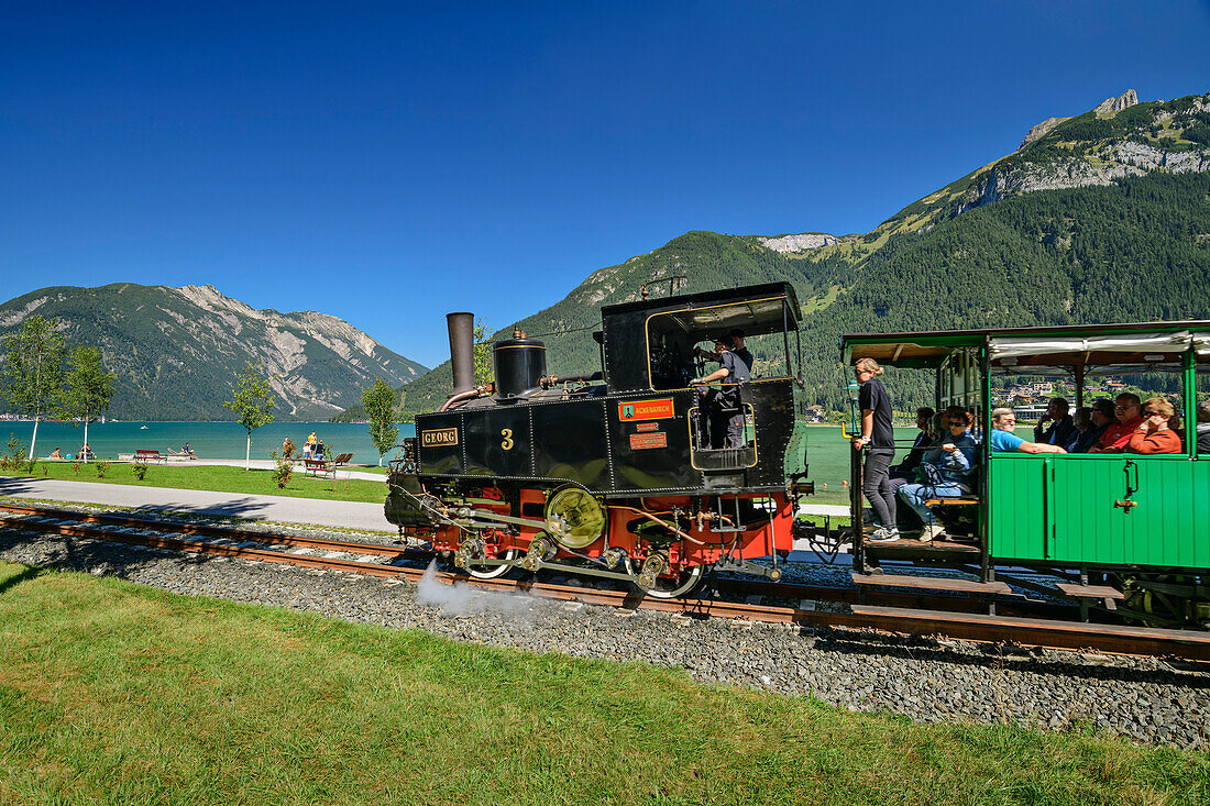  Steam locomotive of the Achenseebahn runs along the Achensee, Karwendel and Rofan in the background, Achensee, Tyrol, Austria 