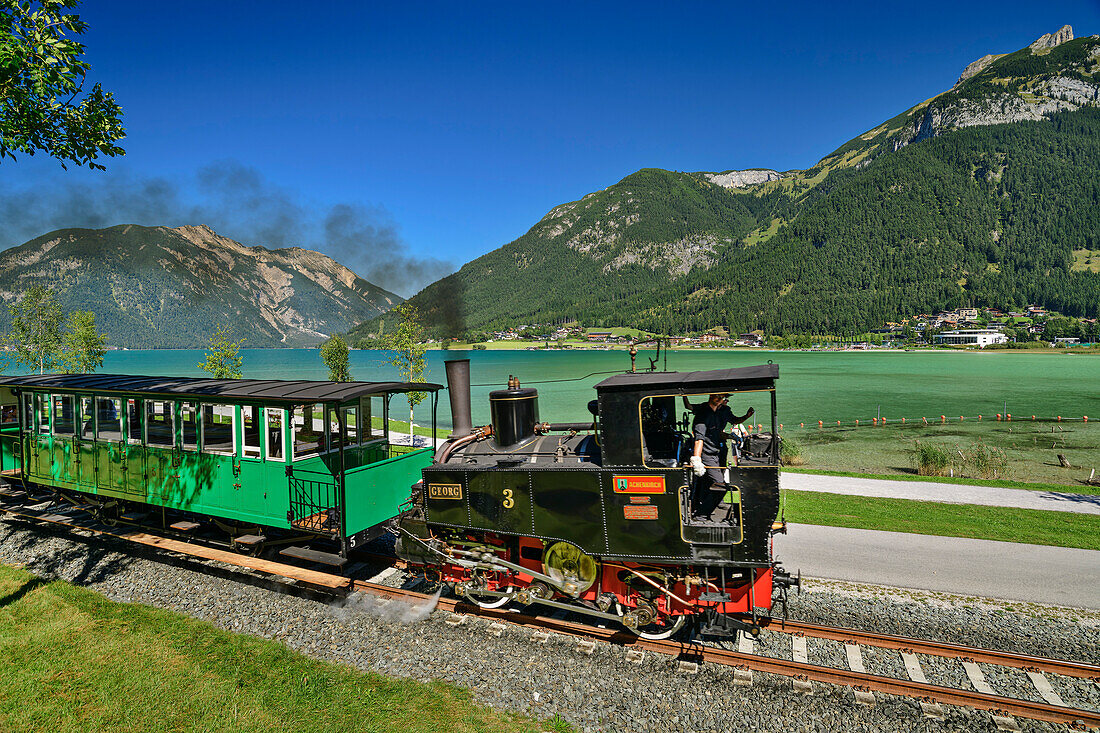  Steam locomotive of the Achenseebahn runs along the Achensee, Karwendel and Rofan in the background, Achensee, Tyrol, Austria 
