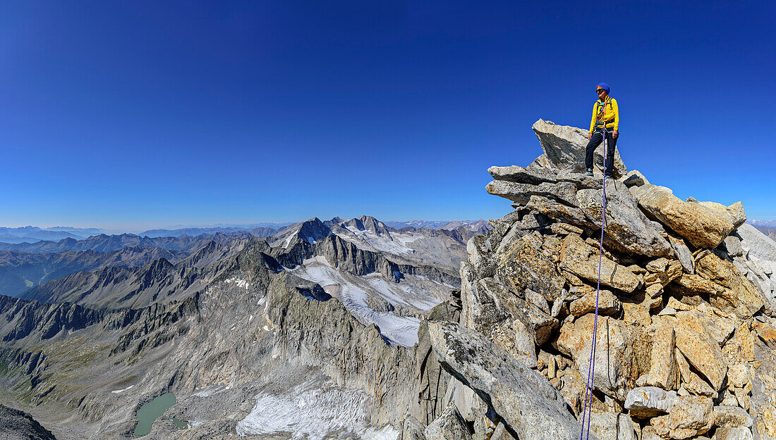 Panorama mit Frau beim Bergsteigen steht auf Felsgrat, Zillertaler Hauptkamm im Hintergrund, am Schwarzenstein, Zillertaler Alpen, Naturpark Zillertaler Alpen, Tirol, Österreich