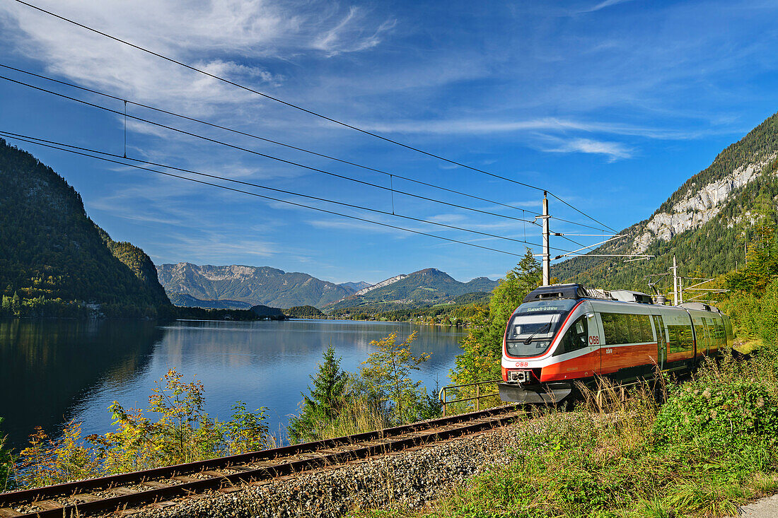  Train runs along Lake Hallstatt, Dachstein in the background, Salzkammergutbahn, Salzkammergut, Upper Austria, Austria 