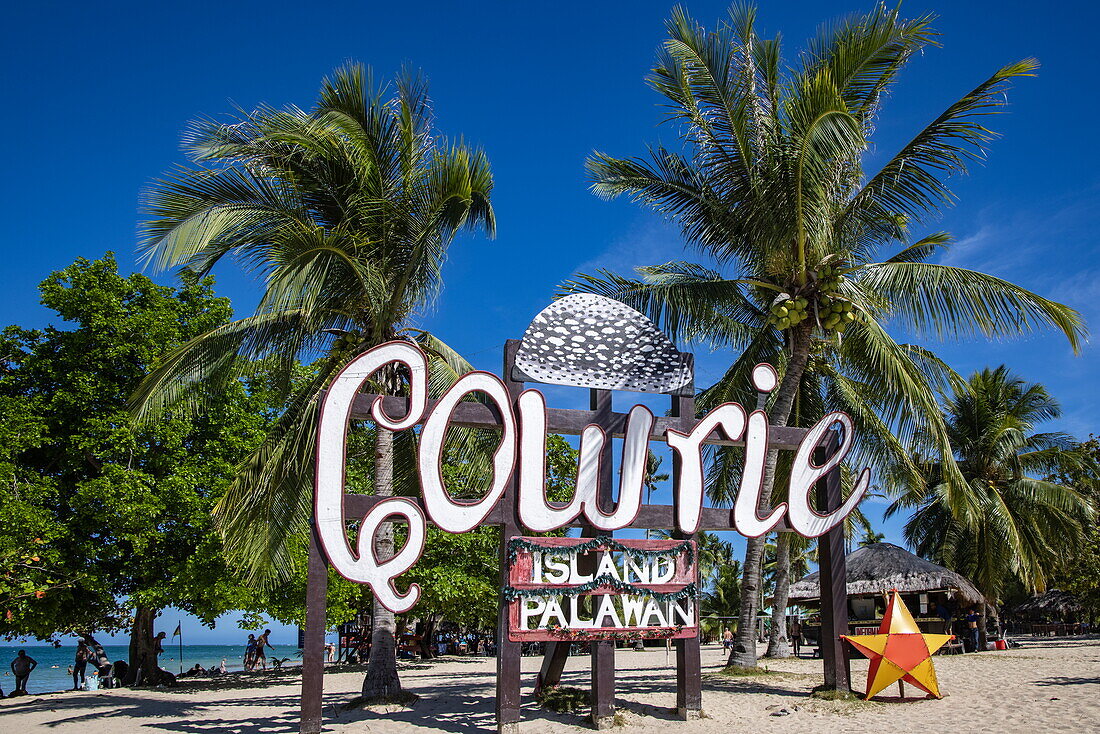 Schild für Cowrie Island vor Kokospalmen, Honda Bay, in der Nähe von Puerto Princesa, Palawan, Philippinen