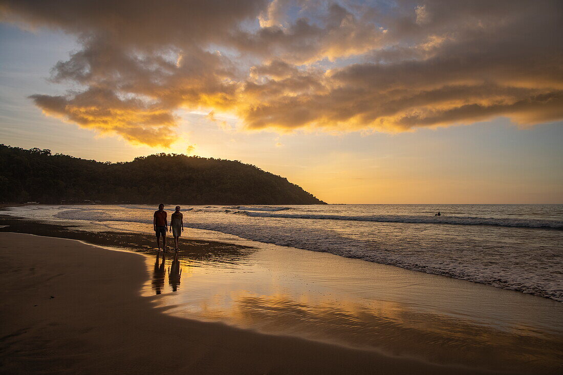  Silhouette of a couple walking along Nagtabon Beach at sunset, Bacungan, near Puerto Princesa, Palawan, Philippines 