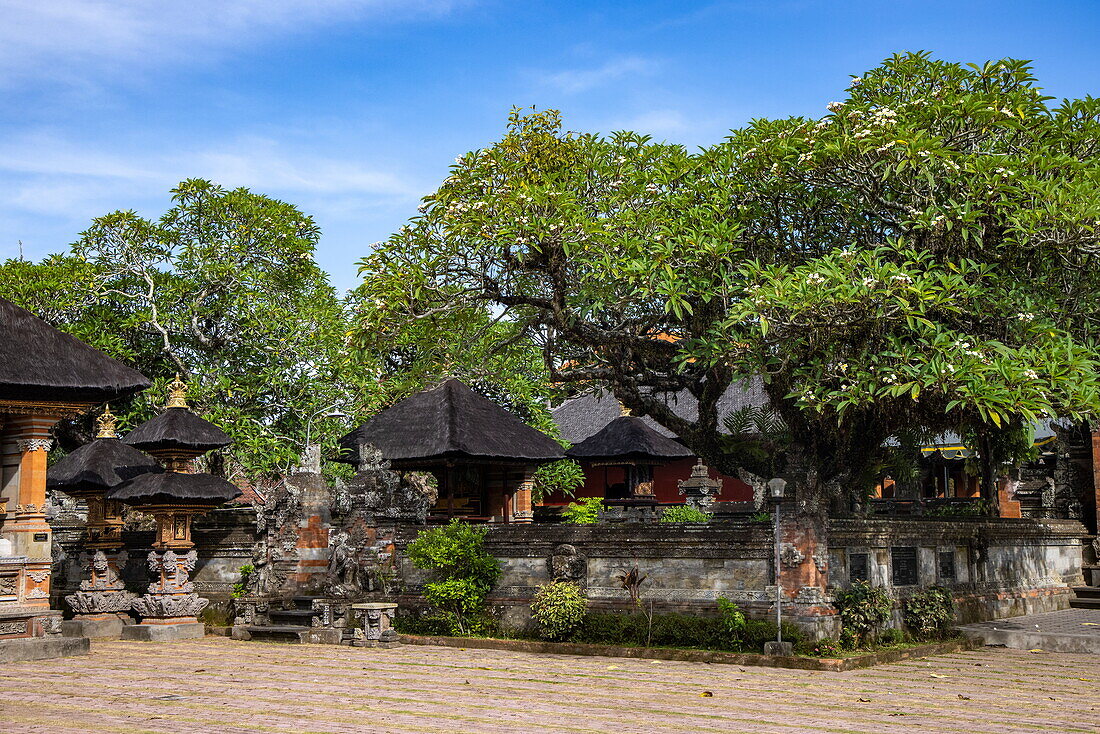 Skulpturen und kleine Pagoden unter Bäumen im Pura Puseh Desa Batuan Hindu-Tempel, Denpasar, Bali, Indonesien, Südostasien