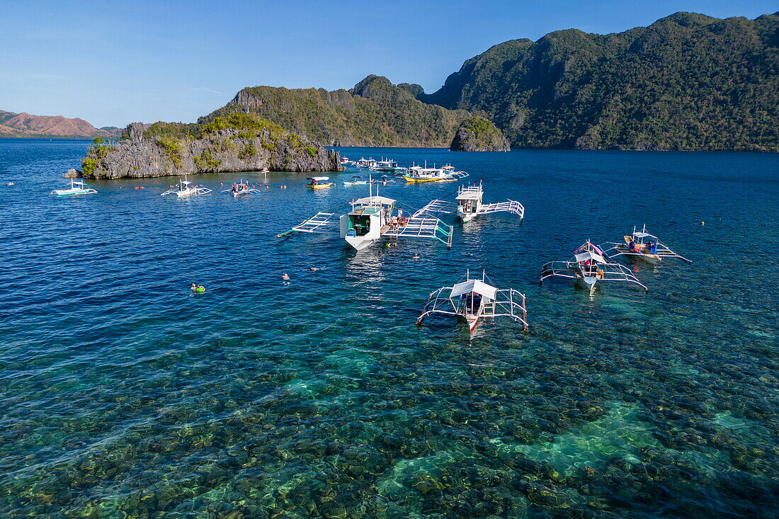 Luftaufnahme von Bangka Auslegerkanus und Schnorchlern in Siete Pecados, Sieben kleine Inseln, Coron, Palawan, Philippinen, Südostasien