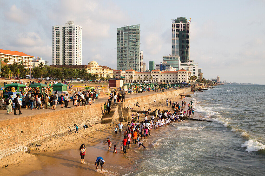 Schulkinder paddeln im Meer am kleinen Sandstrand am Galle Face Green, Colombo, Sri Lanka, Asien