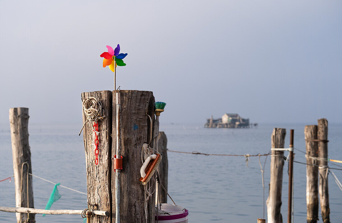 Detailaufnahme von Utensilien an Holzpfahl, im Hintergrung die Fischerhütten auf Stelzen, Lagune von Venedig, Venetien, Italien, Europa