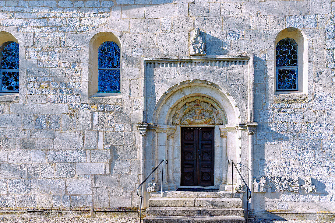 romanische Kirche St. Ulrich in Ainau bei Geisenfeld in Oberbayern in Deutschland: romanisches Portal mit Darstellung der armen Seelen in Abrahams Schoß, darüber lehrender Christus, rechts Reliefsteine mit Einzug Christi in Jerusalem