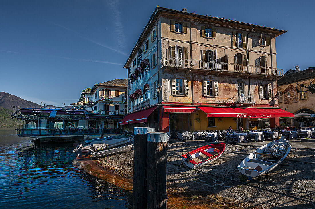  Rowing boats in the foreground, view of Isola San Giulio from the port of Orta San Giulio, Piazza Motta, Hotel Leon d&#39;Oro in the background, Orta San Giulio, Lake Orta is a northern Italian lake in the northern Italian, Lago d&#39;Orta, or Cusio, region of Piedmont, Italy, Europe 