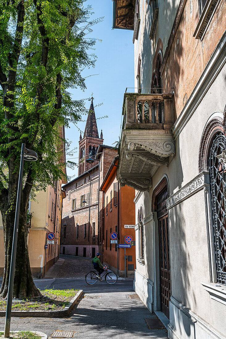  Cyclist in alley with bell tower of cathedral, Cremona, Cremona province, Lombardy, Italy, Europe 
