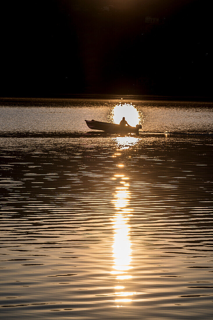 Motorboot im Gegenlicht bei Sonnenaufgang, Pella, Westufer des Ortasees, Ortasee Lago d’Orta, Provinz Novara, Region Piemont, Italien