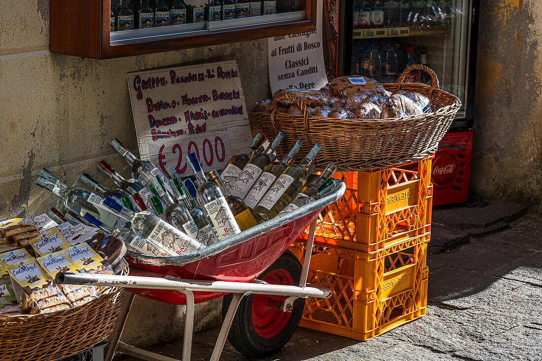  Shop with wine bottles in wheelbarrow, alleys in Orta San Giulio, Lake Orta is a northern Italian lake in the northern Italian, Lago d&#39;Orta, or Cusio, region of Piedmont, Italy, Europe 