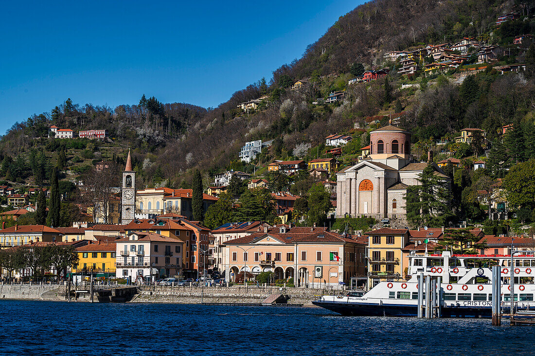 Blick auf Fähre im Hafen, Kirche Chiesa di Sant' Ambrogio und Häuser am Hang, Laveno-Mombello, Provinz Varese, Lago Maggiore, Lombardei, Italien