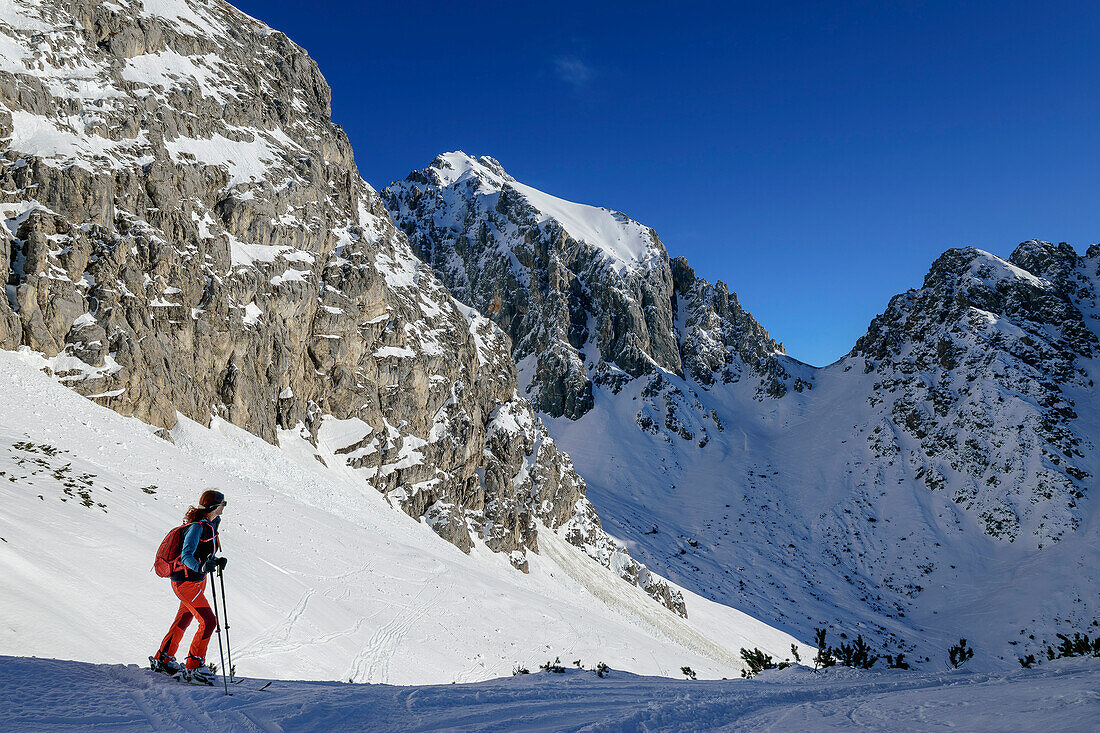  Woman on ski tour stands in the Hölltörl and looks at the Mieminger Mountains, Hölltörl, Grünstein bypass, Mieminger Mountains, Tyrol, Austria 