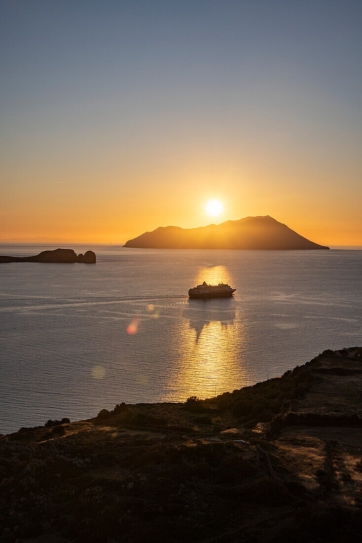 Silhouette des Kreuzfahrtschiffs Celestyal Journey (Celestyal Cruises) und Inseln bei Sonnenuntergang, Plaka, Milos, Kykladen, Südliche Ägäis, Griechenland, Europa