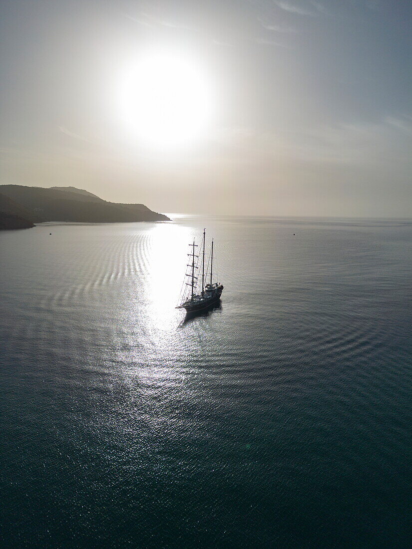 Luftaufnahme von Segelkreuzfahrtschiff Running on Waves (M'Ocean) bei Sonnenaufgang in der Bucht, Insel Poros, Attika, Peloponnes, Ägäis, Griechenland, Europa