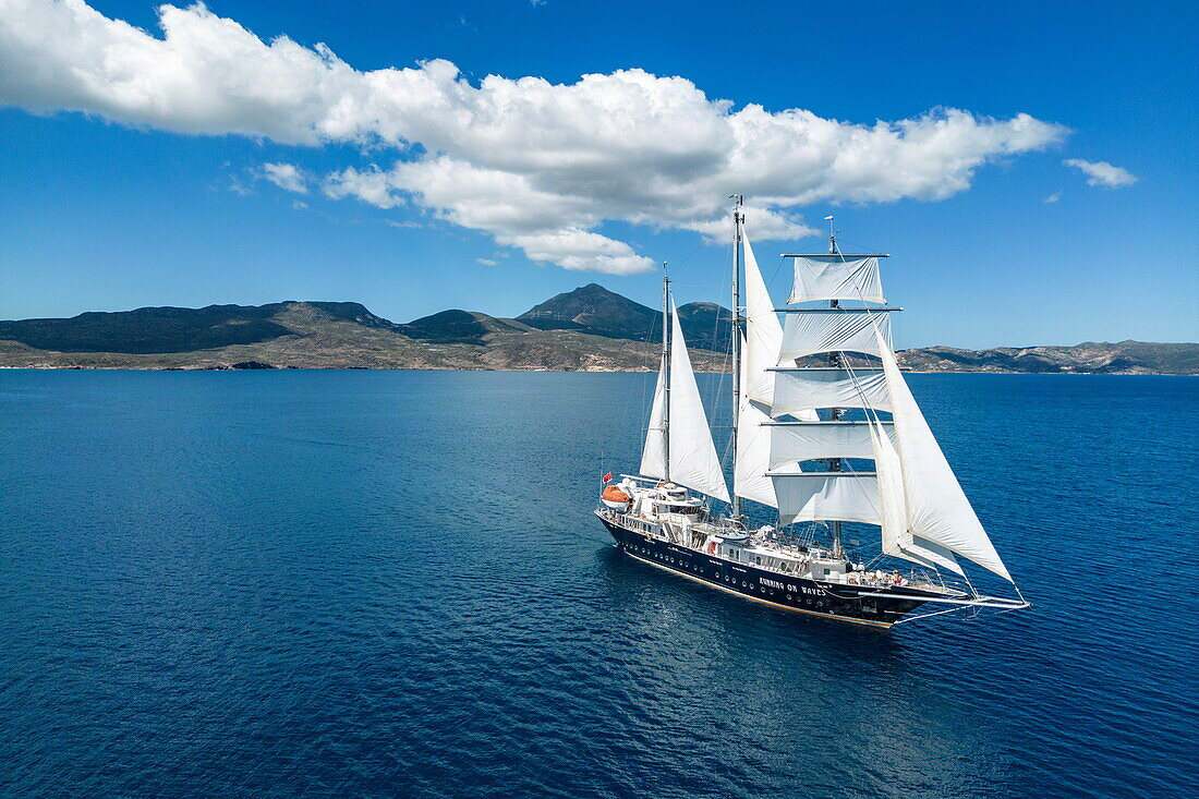 Luftaufnahme des dreimastigen Segelkreuzfahrtschiffs Running on Waves (M'Ocean) unter Segeln, Adamas, Milos, Südliche Ägäis, Kykladen, Griechenland, Europa