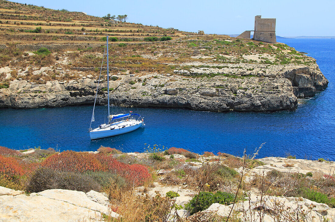 Yacht and watchtower at entrance to Mgarr ix-Xini coastal inlet, island of Gozo, Malta