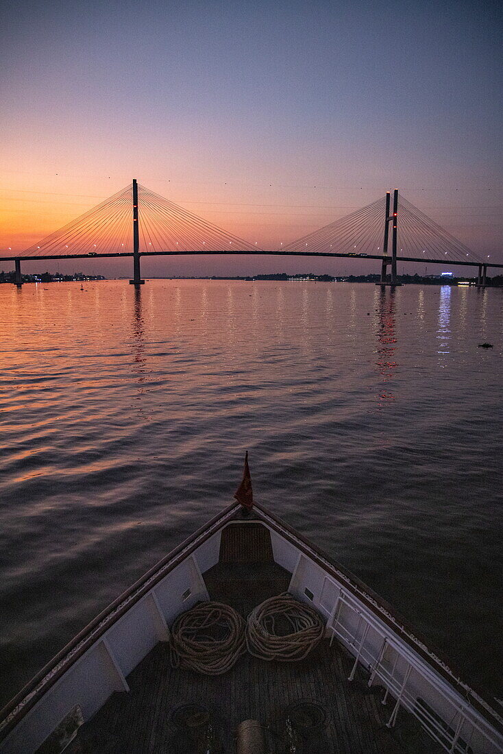  Bow of the river cruise ship The Jahan (Heritage Line) on the Mekong with the Cao Lanh Bridge at sunset, near Cao Lanh (Cao Lãnh), Dong Thap (Đồng Tháp), Vietnam, Asia 