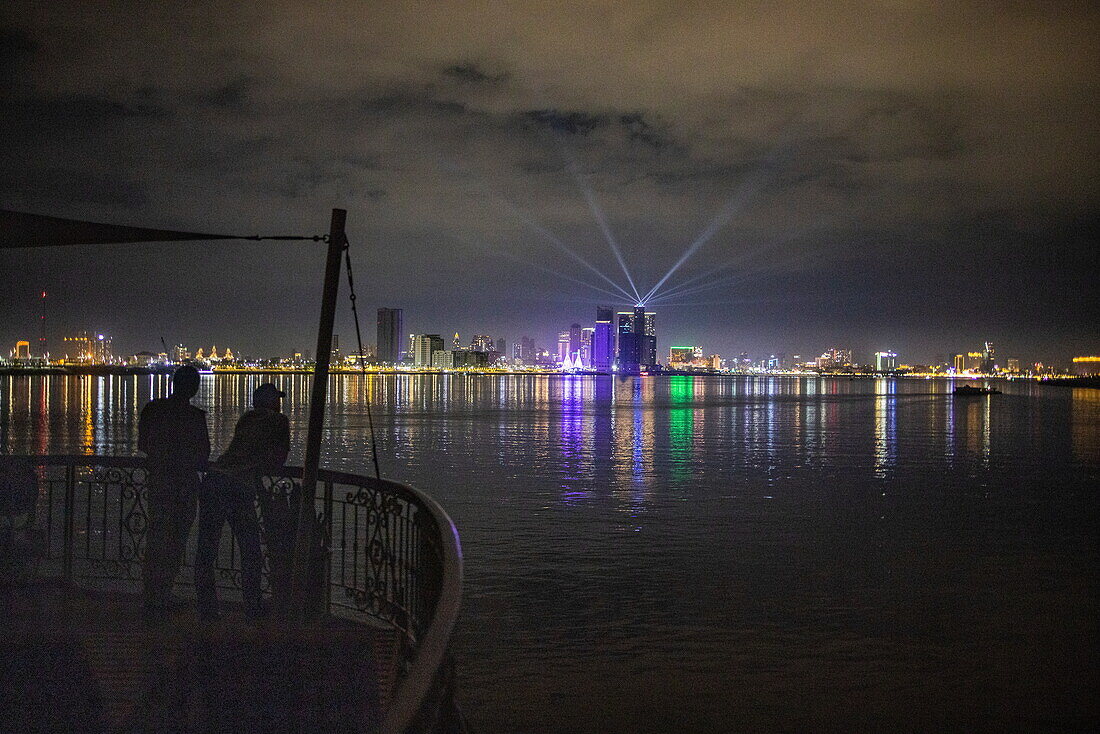  Two people on the front deck of the river cruise ship The Jahan (Heritage Line) on the Mekong with skyline and city lights at night, Phnom Penh, Phnom Penh, Cambodia, Asia 