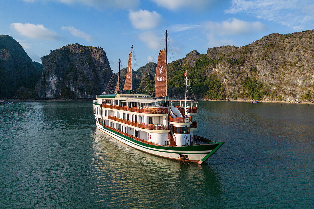  Aerial view of cruise ship Ylang (Heritage Line) with full sails in a bay surrounded by karst islands, Lan Ha Bay, Haiphong, Vietnam, Asia 