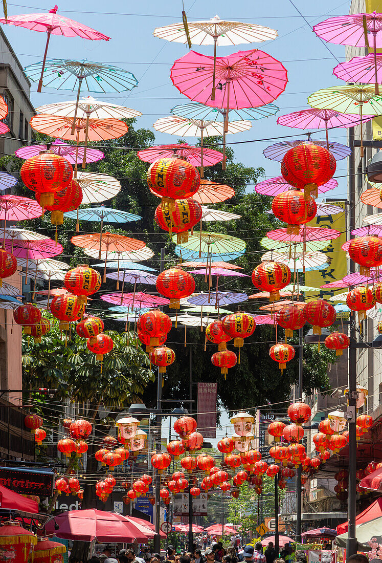 Red paper Chinese lanterns and umbrellas hanging above the street in Chinatown, Mexico City, Mexico advertising various restaurants