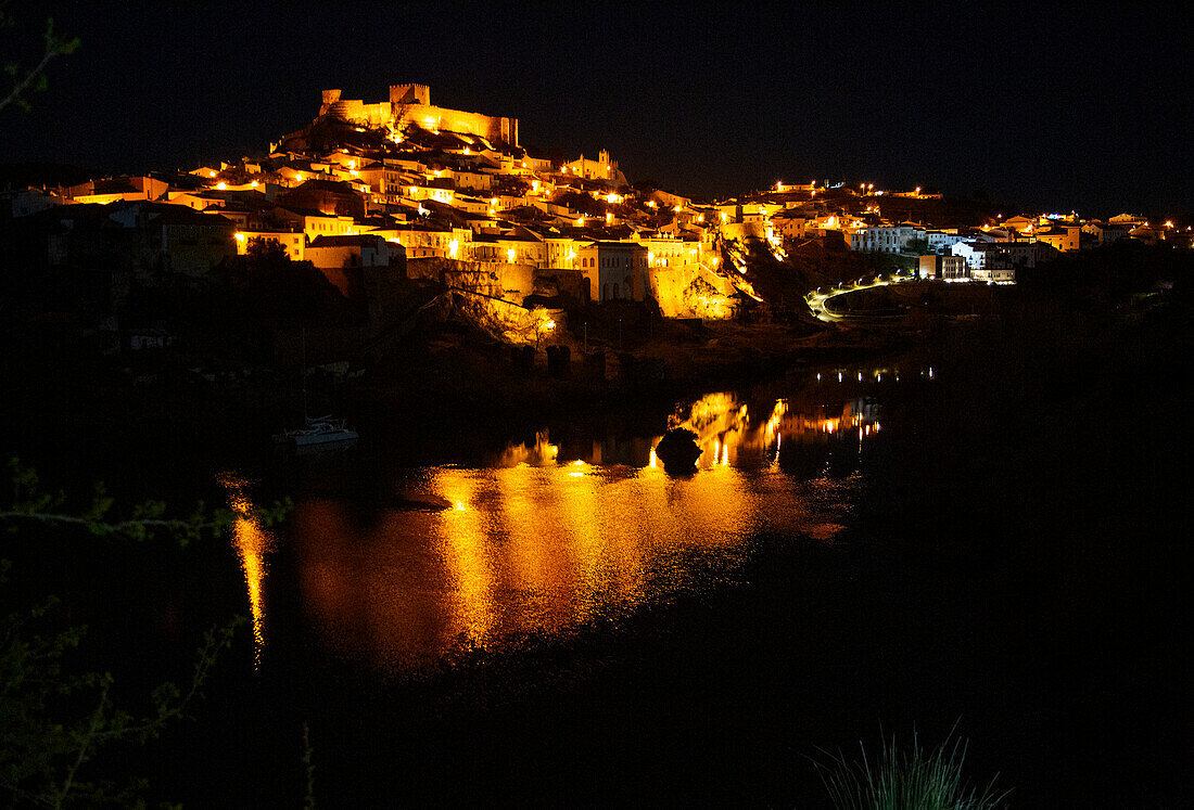 Historic hilltop walled medieval village of Mértola with castle, on the banks of the river Rio Guadiana, Baixo Alentejo, Portugal, Southern Europe nighttime with illumination of orange street lights