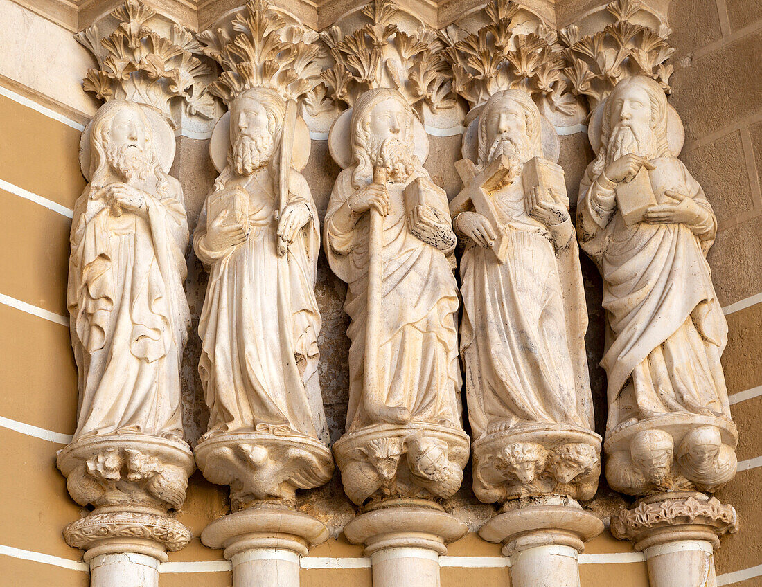 Historic Roman Catholic cathedral church of Évora, Sé de Évora, in the city centre, Basilica Cathedral of Our Lady of Assumption. This image shows details of the carved Gothic period Apostles in the main doorway entrance. Marble columns are occupied by huge statues of the Apostles dating from the 1330s.