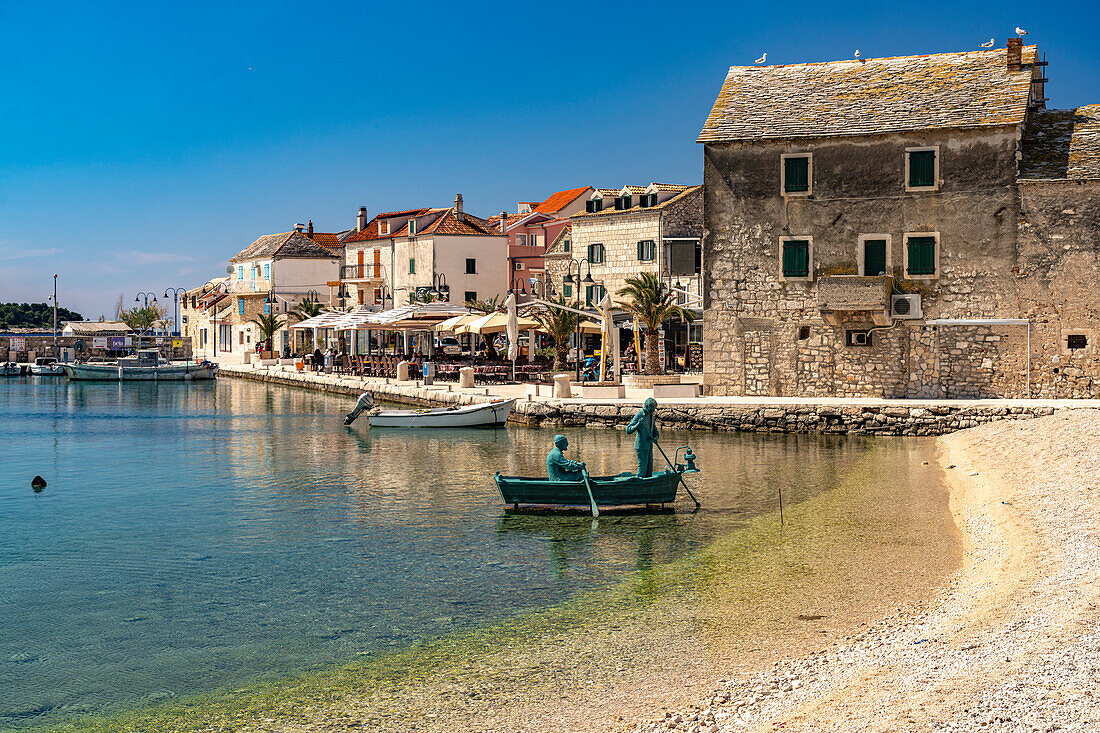  Sculpture rowing boat on the beach and the old town of Primosten, Croatia, Europe  