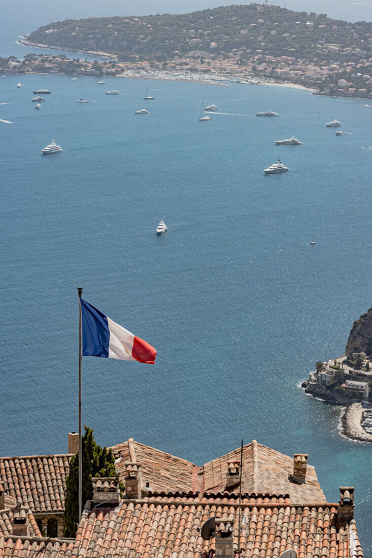 Französische Fahne weht im Wind mit dem blauen Meer und Yachten im Hintergrund in Nizza, Frankreich