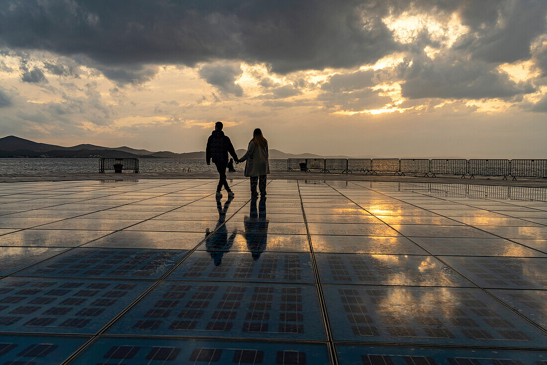 Paar auf der Solarinstallation Gruß an die Sonne bei Sonnenuntergang, Zadar, Kroatien, Europa