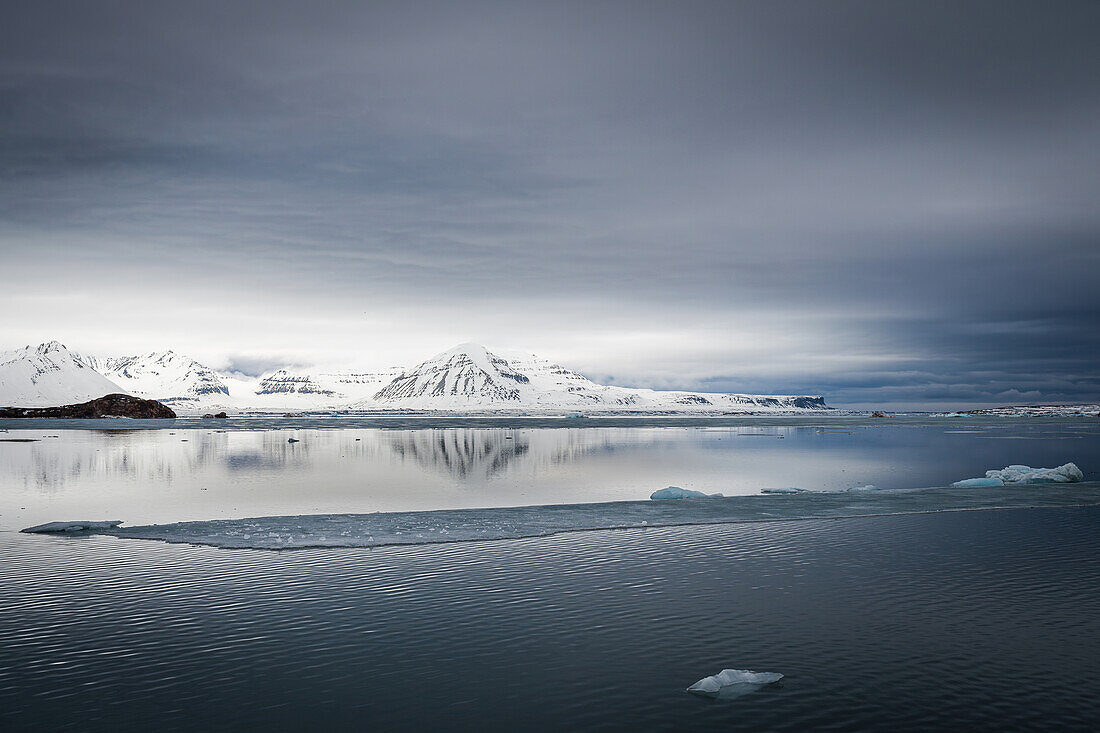 Blick auf Eisschollen und schneebedeckte Berge im Isfjord von Spitzbergen, Svalbard, Norwegen, Arktis