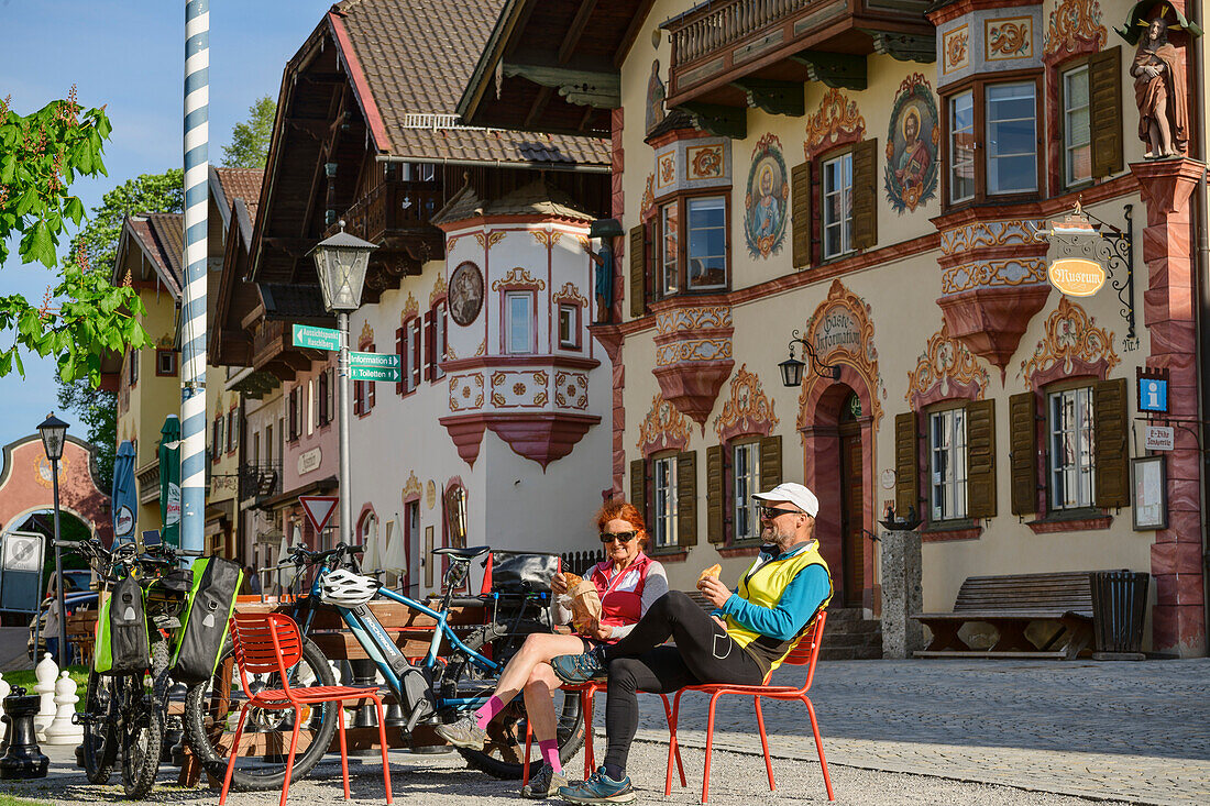  Man and woman cycling taking a break in Neubeuern, Neubeuern, Lake Constance-Königssee cycle path, Upper Bavaria, Bavaria, Germany 