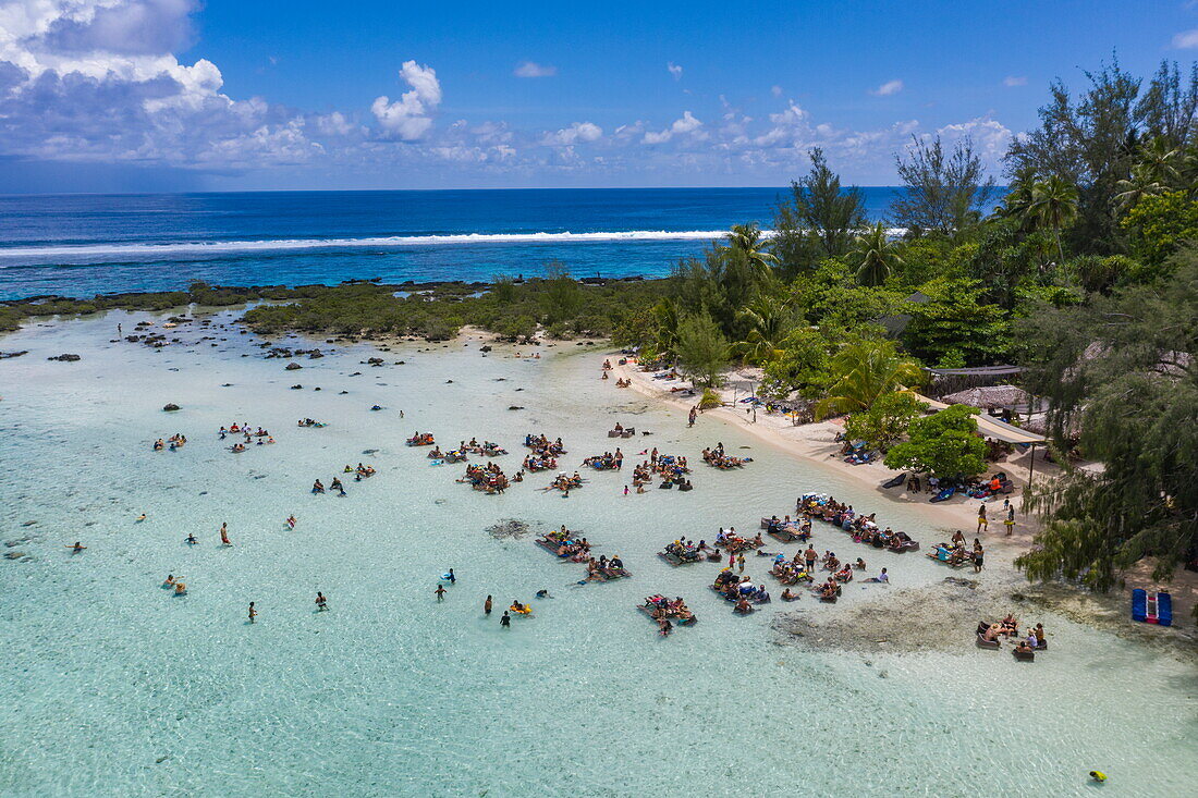  Aerial view of people relaxing and listening to live music while sitting at picnic tables in the lagoon, Moorea, Windward Islands, French Polynesia, South Pacific 